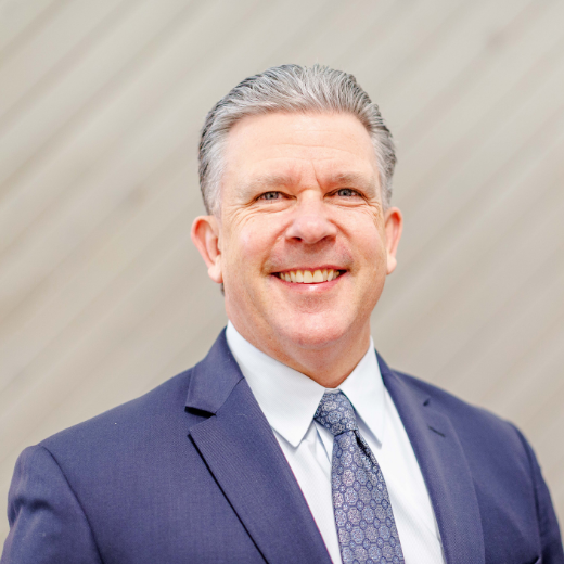 Man in a blue suit against a beige background